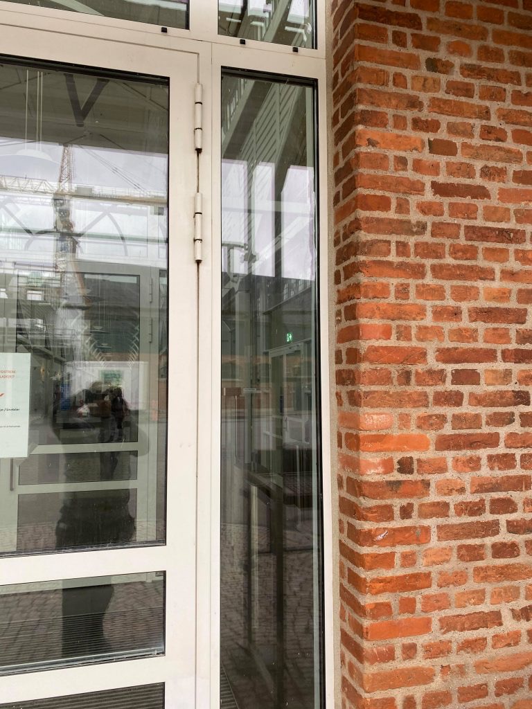 Besandet fuge ved en glasdør i rødt murværk